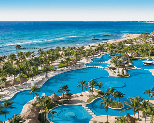 Aerial view of the beautiful ocean and stunning winding pools surrounded by lush landscaping at Mayan Palace at Vidanta Riviera Maya.